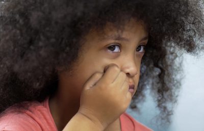 Depressed little girl suffering Down syndrome sitting at table, healthcare